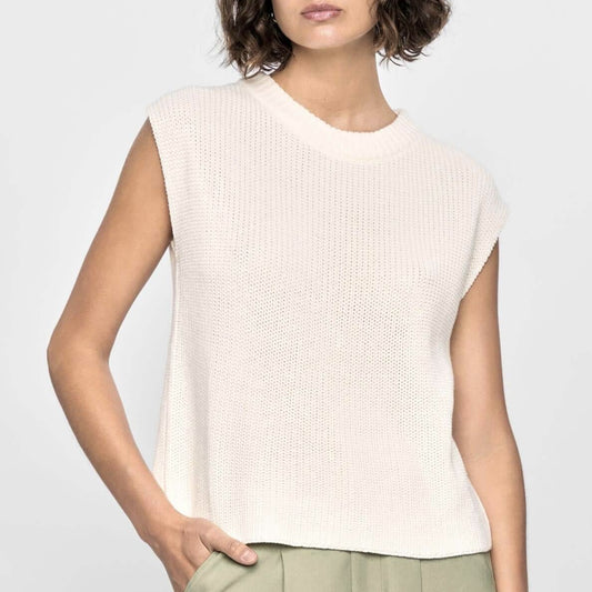 Woman wearing a light beige sleeveless top against a plain background